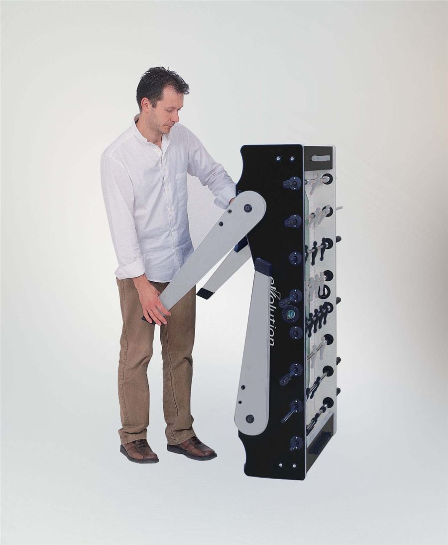 Ein Mann in weißem Hemd und braunen Hosen klappt einen schwarzen Tischkicker zusammen.