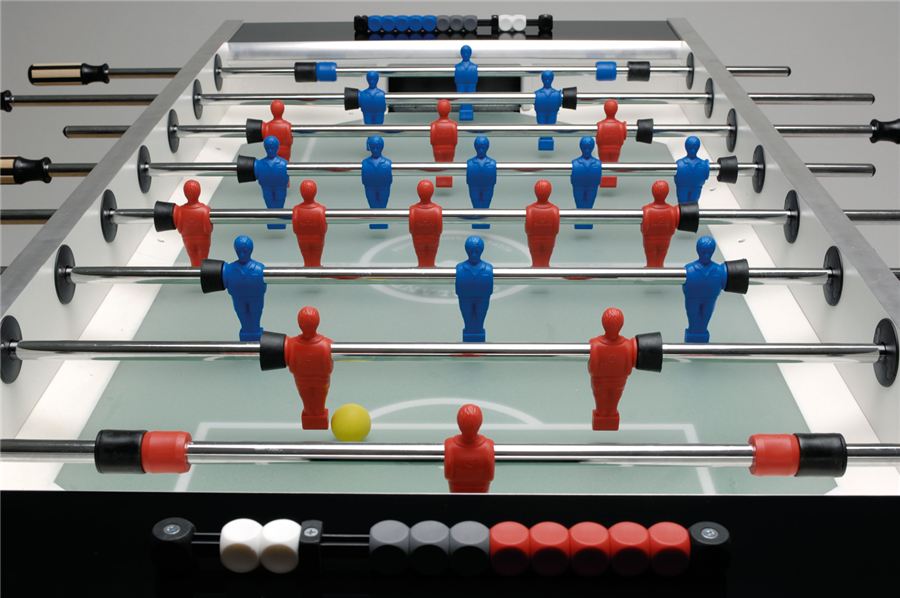 Tischkicker mit roten und blauen Spielfiguren, gelbem Ball und Zählleisten für die Punkteanzeige am Spielfeldrand.