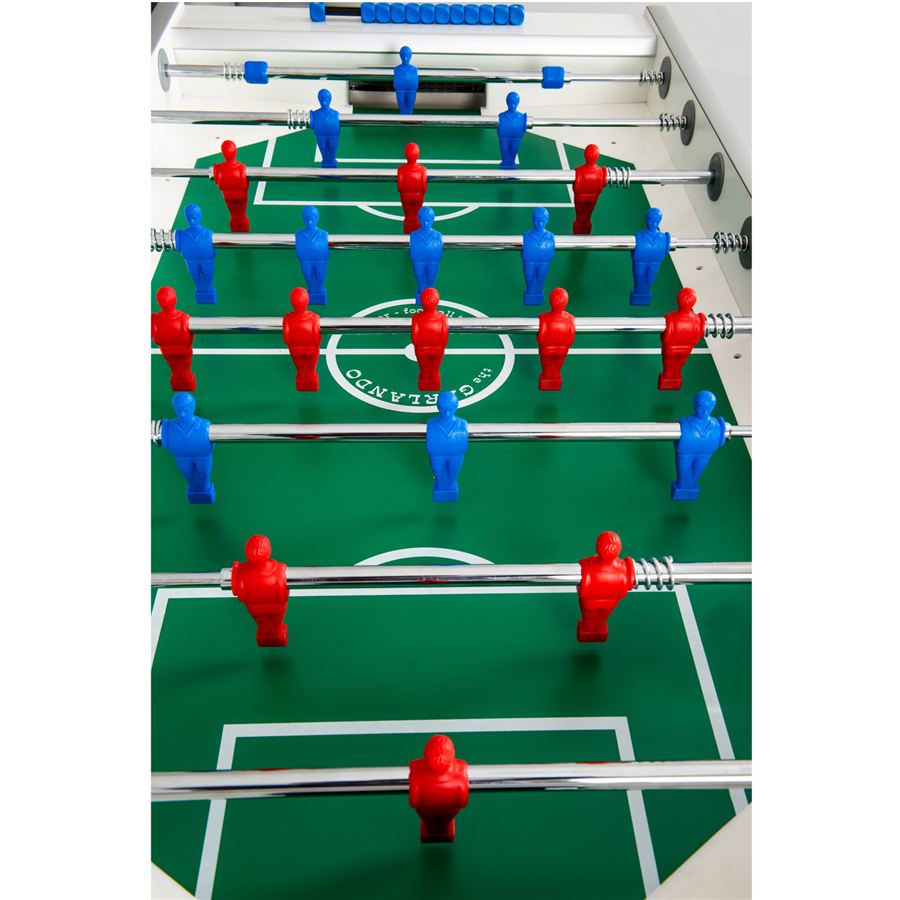 Tischfußballspiel mit roten und blauen Spielfiguren auf grünem Spielfeld, bereit für ein spannendes Match.