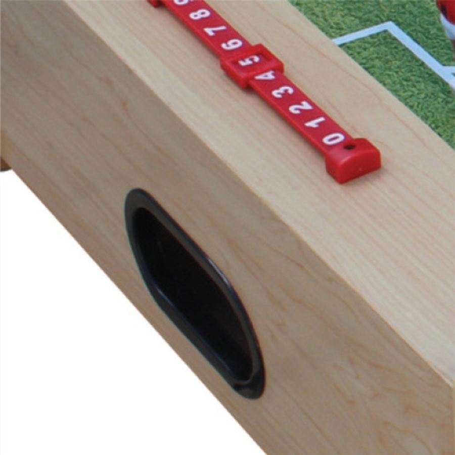 Nahaufnahme eines Kickertischs mit rotem Torzähler und Ballauswurf an der Seite, Spielfeldkante oben rechts sichtbar.