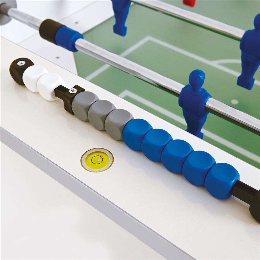 Nahaufnahme eines Kickertischs mit blauen Spielfiguren, farbigen Zählsteinen und Spielfeld im Hintergrund.